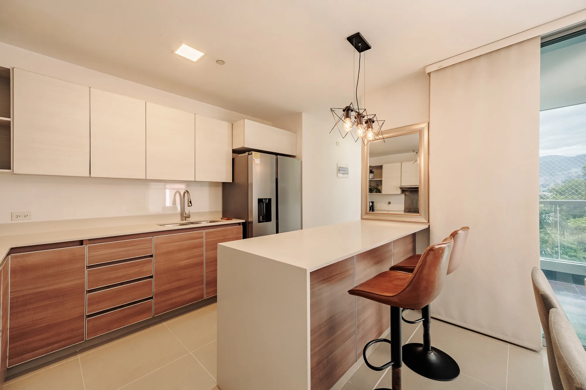 Kitchen with an island, bar stools, full appliances and a window onto the gardens at Balcón Verde, El Poblado