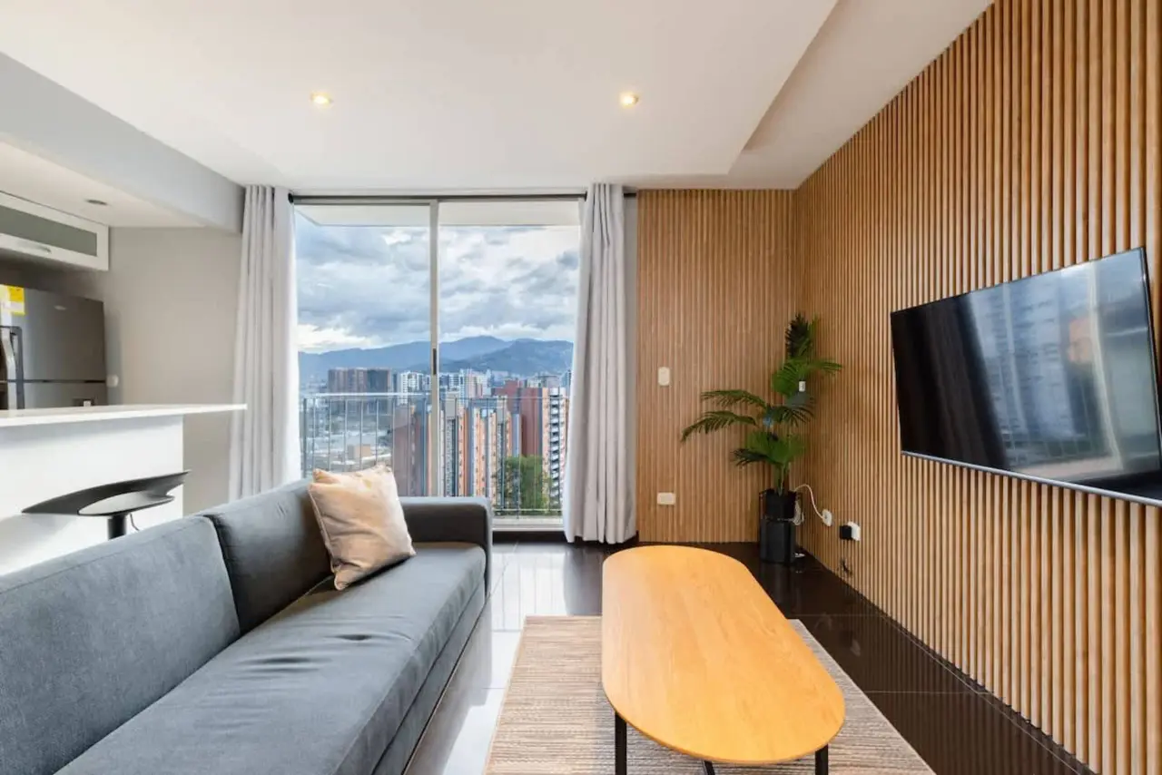The living room with the wall-mounted TV and the mountains beyond the balcony