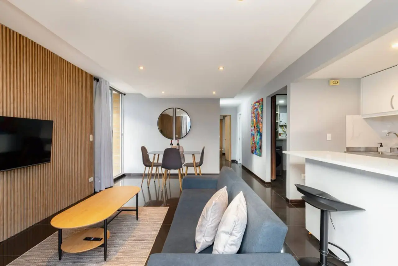 The apartment seen end to end — living, dining and the round mirror on the far wall