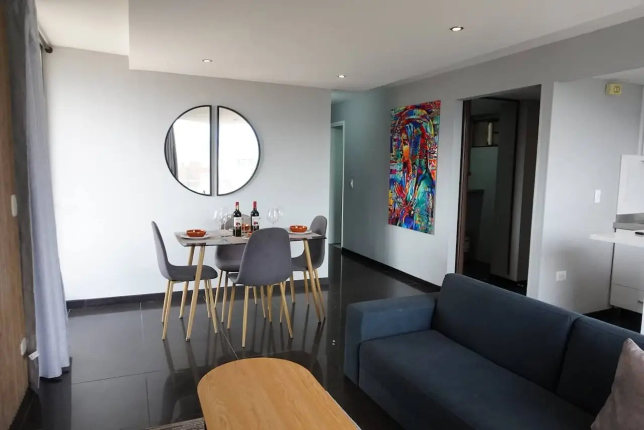 Dining table for four beside the living room, under the circular mirror