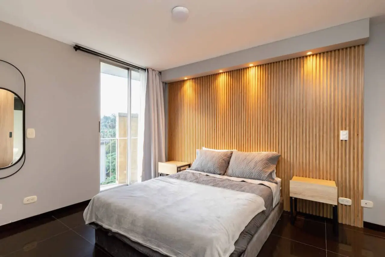 The main bedroom with daylight from the window and lit timber slats
