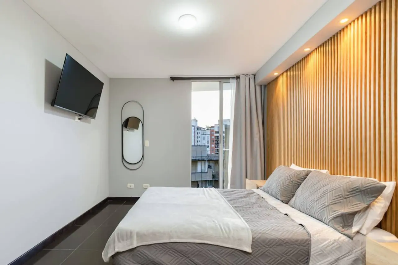 Bedroom with a wall-mounted TV and a window onto the city