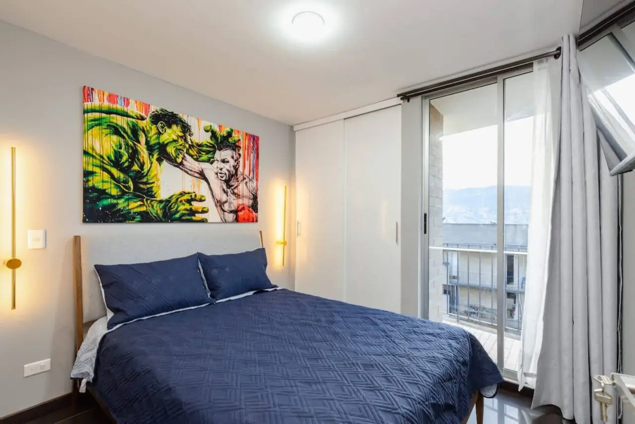 The second bedroom, with a pop-art canvas over the bed and the balcony door alongside