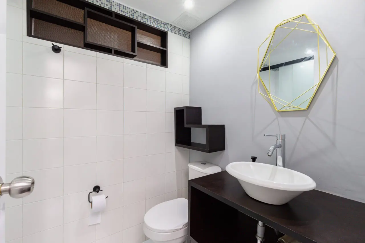 Bathroom with a hexagonal mirror and a stone basin