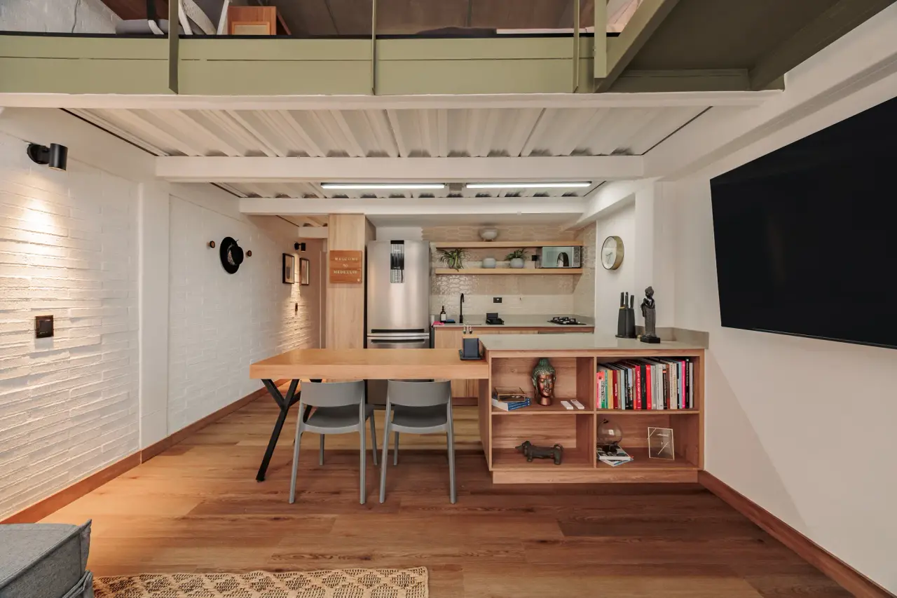 Dining table, bookshelf and kitchen along the loft’s long wall