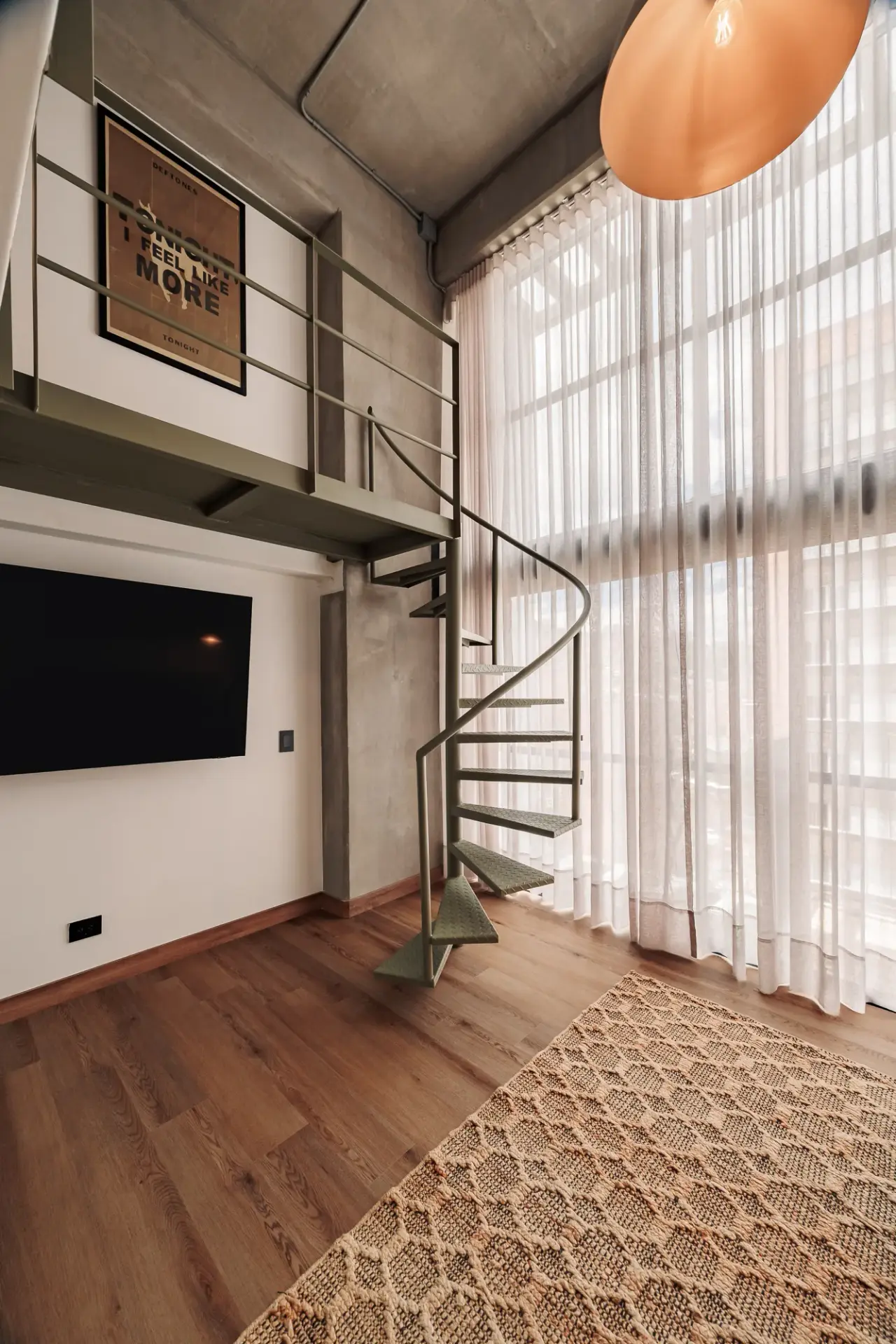The living-room TV and the spiral stair against the full-height curtains