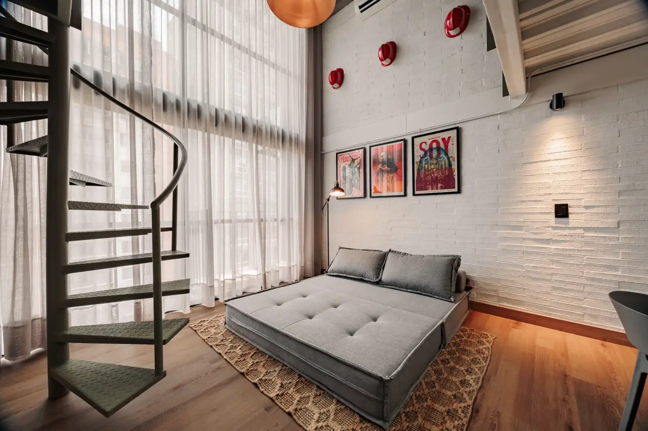 Sofa and spiral stair under the framed prints at Centro Loft