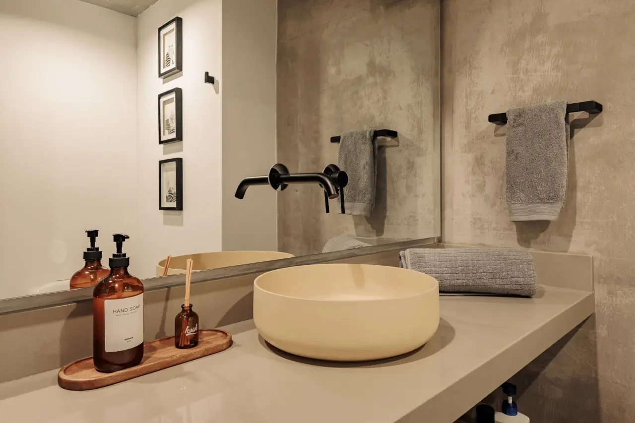 Bathroom vanity — a vessel basin on a concrete counter with a wall-mounted tap