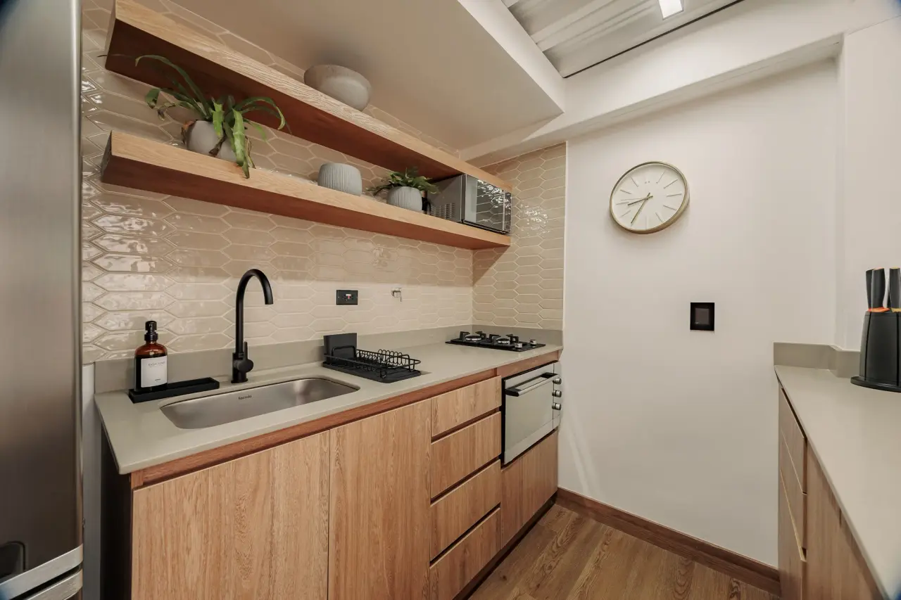 Kitchen with sink, gas hob, open shelves and the clock