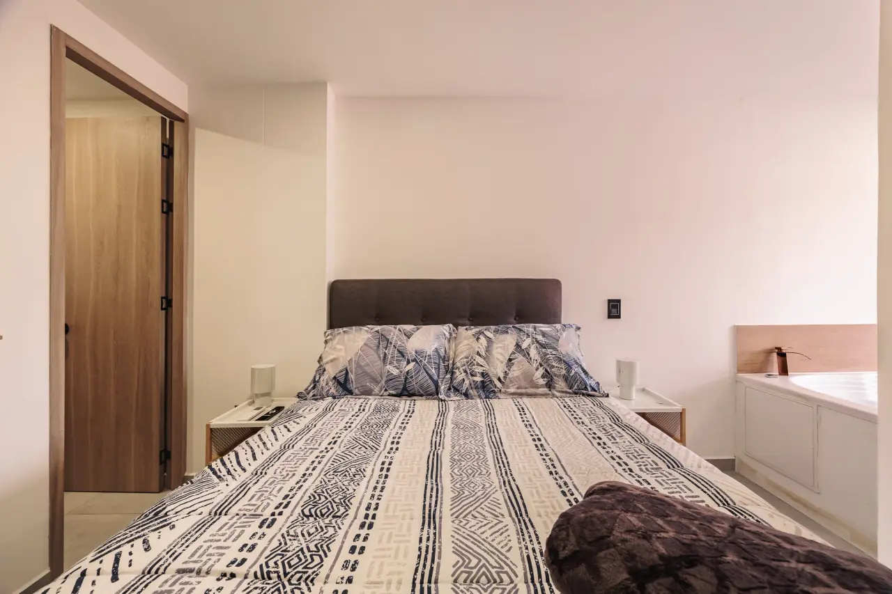 Main bedroom: queen bed with a padded headboard and the jacuzzi beside it