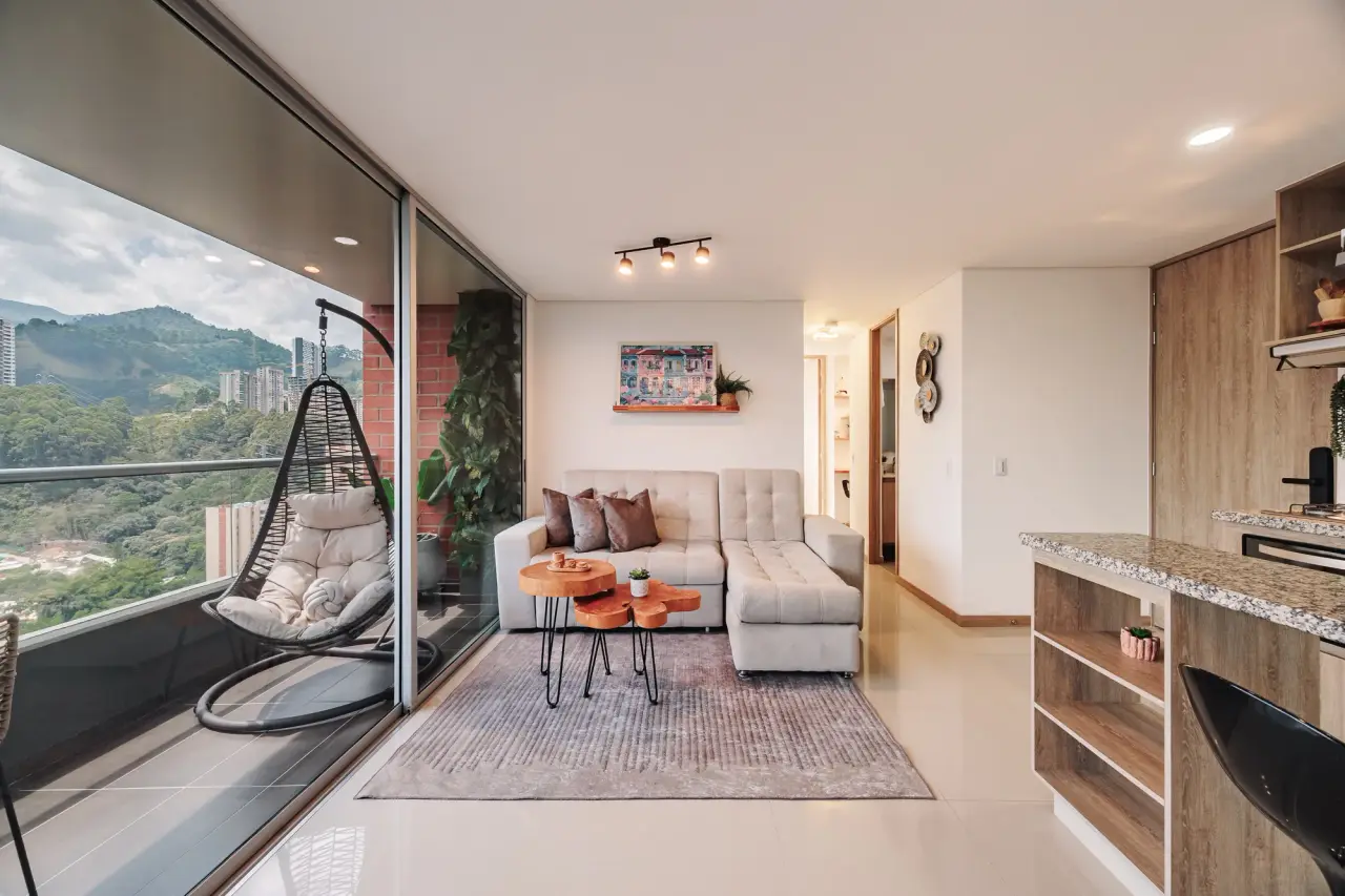 Living room corner: hanging chair, sofa and rug, with the kitchen bar to the right